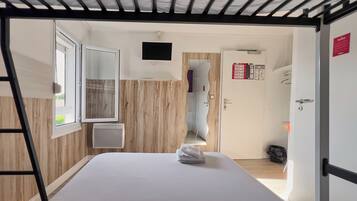 A room with a bed, a window, a TV, and a door with a sign.