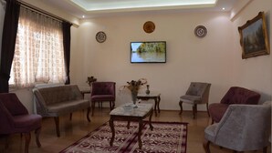 A living room with a sofa, armchairs, a coffee table, and a television on the wall. - Aygun Hotel (Avanos)