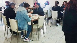 A dining area with multiple tables and chairs, a tiled floor, and a plain wall with a clock. - Aygun Hotel (Avanos)