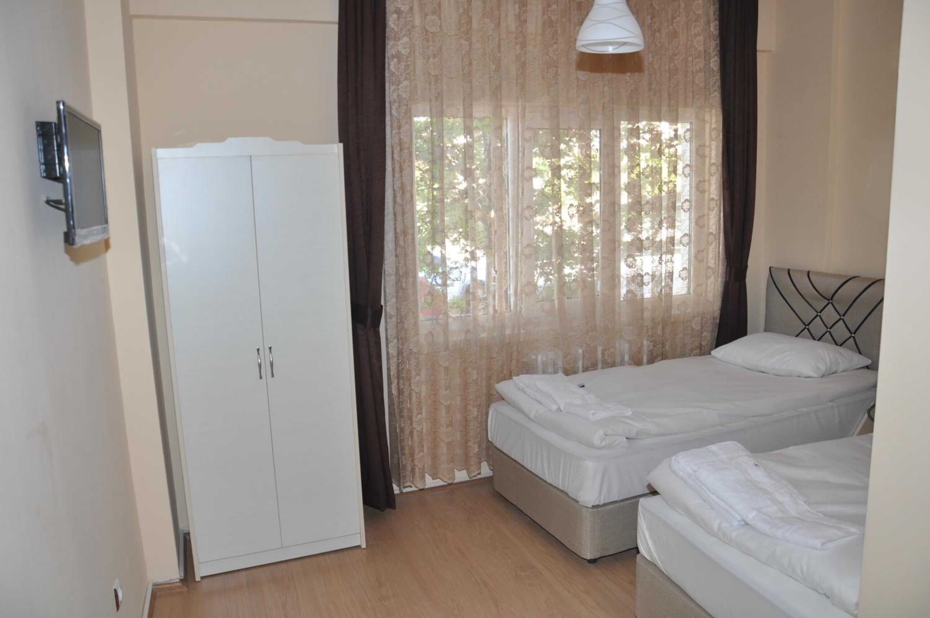 Un dormitorio con dos camas, un armario y una ventana con cortinas.