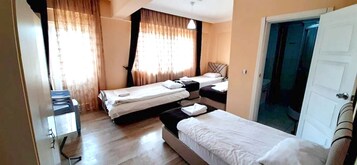 A hotel room with two beds, a desk, and a door.