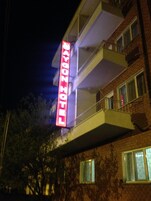 Un edificio de varios pisos con un llamativo letrero de neón rojo en el exterior.