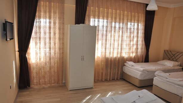 A hotel room with a wardrobe, two beds, and a television. - Aygun Hotel (Avanos)