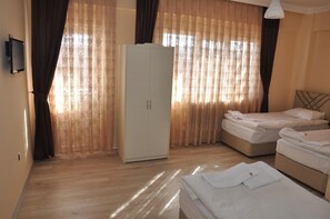 A hotel room with a wardrobe, two beds, and a television. - Aygun Hotel (Avanos)