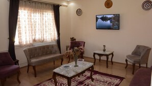 A living room with a sofa, armchairs, a coffee table, and a television. - Aygun Hotel (Avanos)