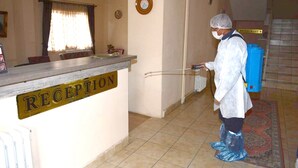 A reception area with a sign labeled "RECEPTION," a clock on the wall, and a person in protective gear. - Aygun Hotel (Avanos)
