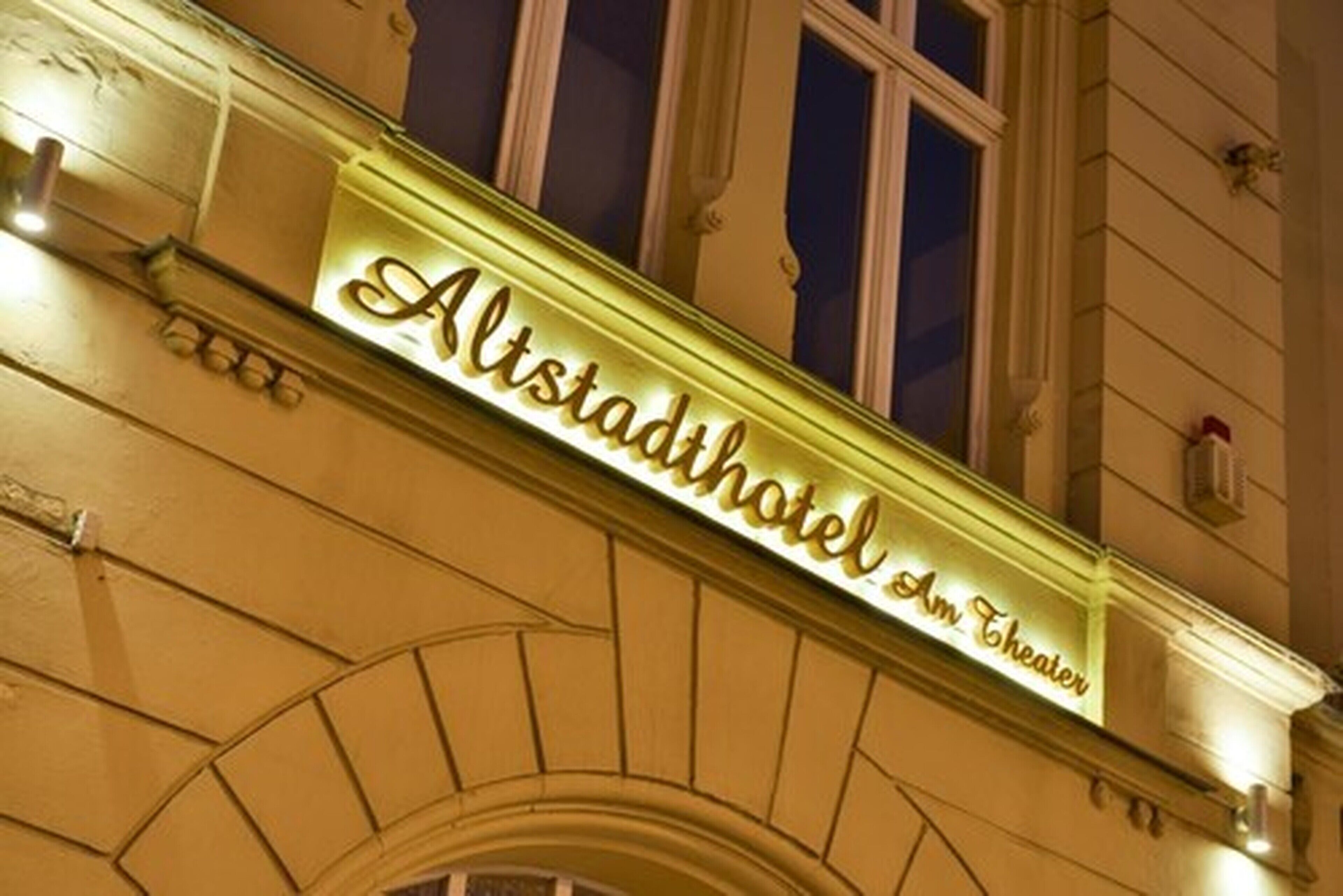 Exterior del Alstadihotel Am Theater con un llamativo letrero iluminado.