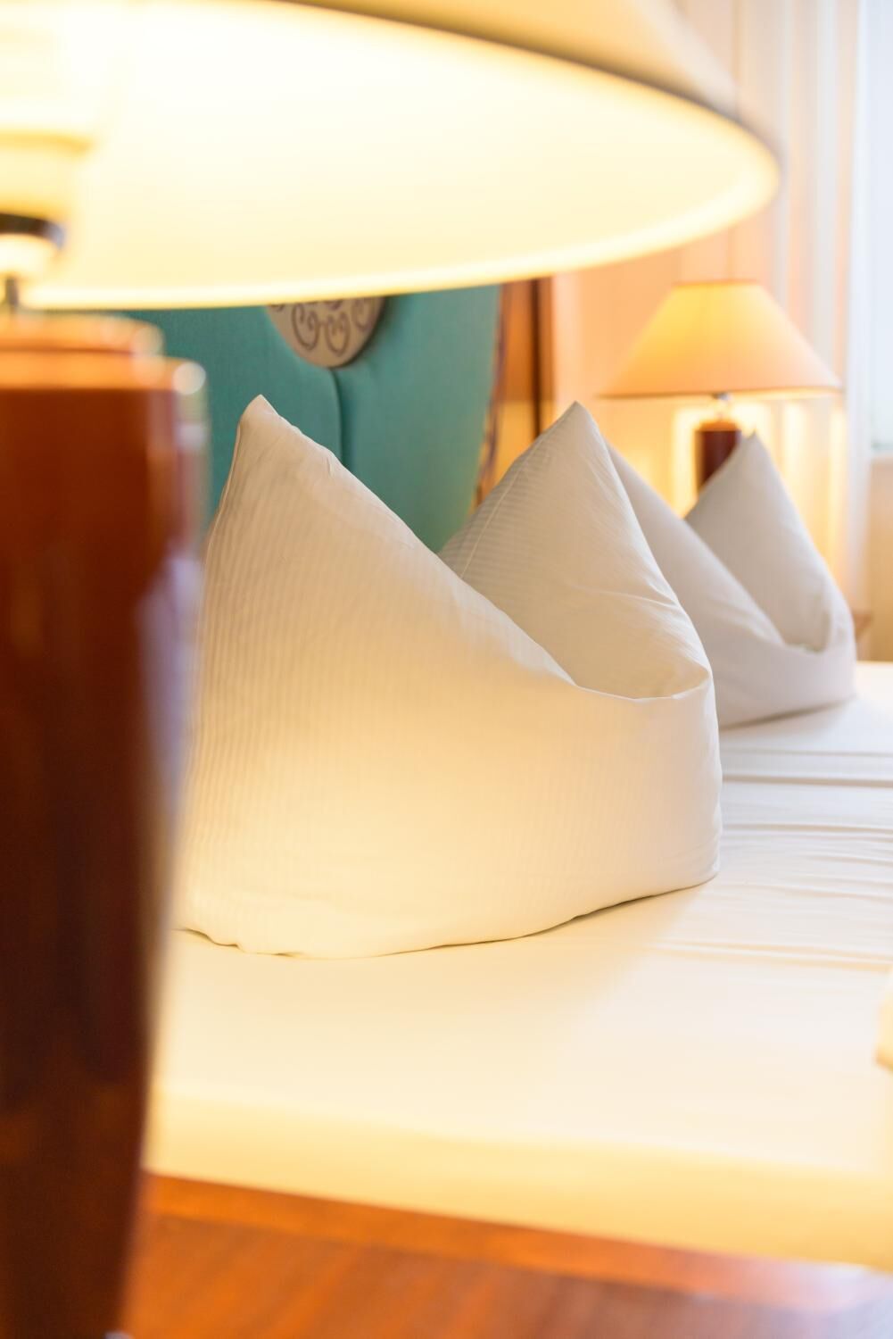 A neatly arranged bed with pillows and a lamp.