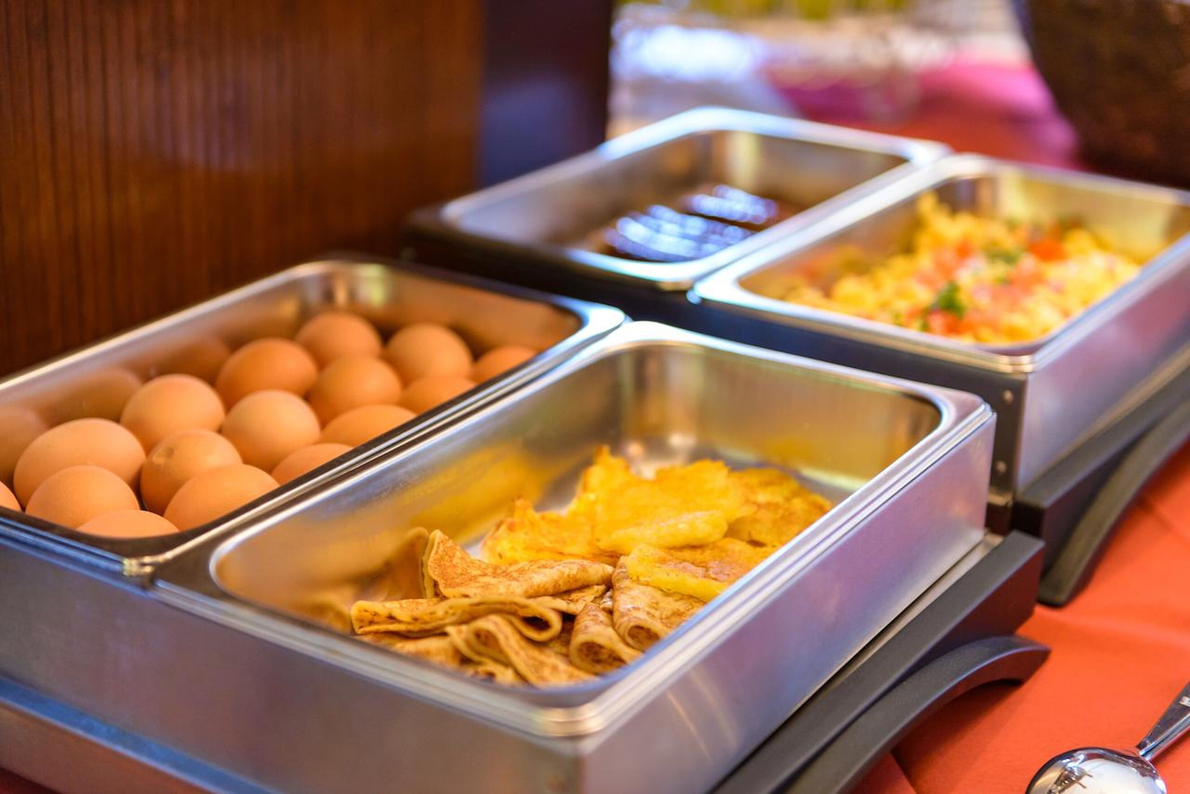 A buffet with various food items including eggs, waffles, and a dish with pineapple.