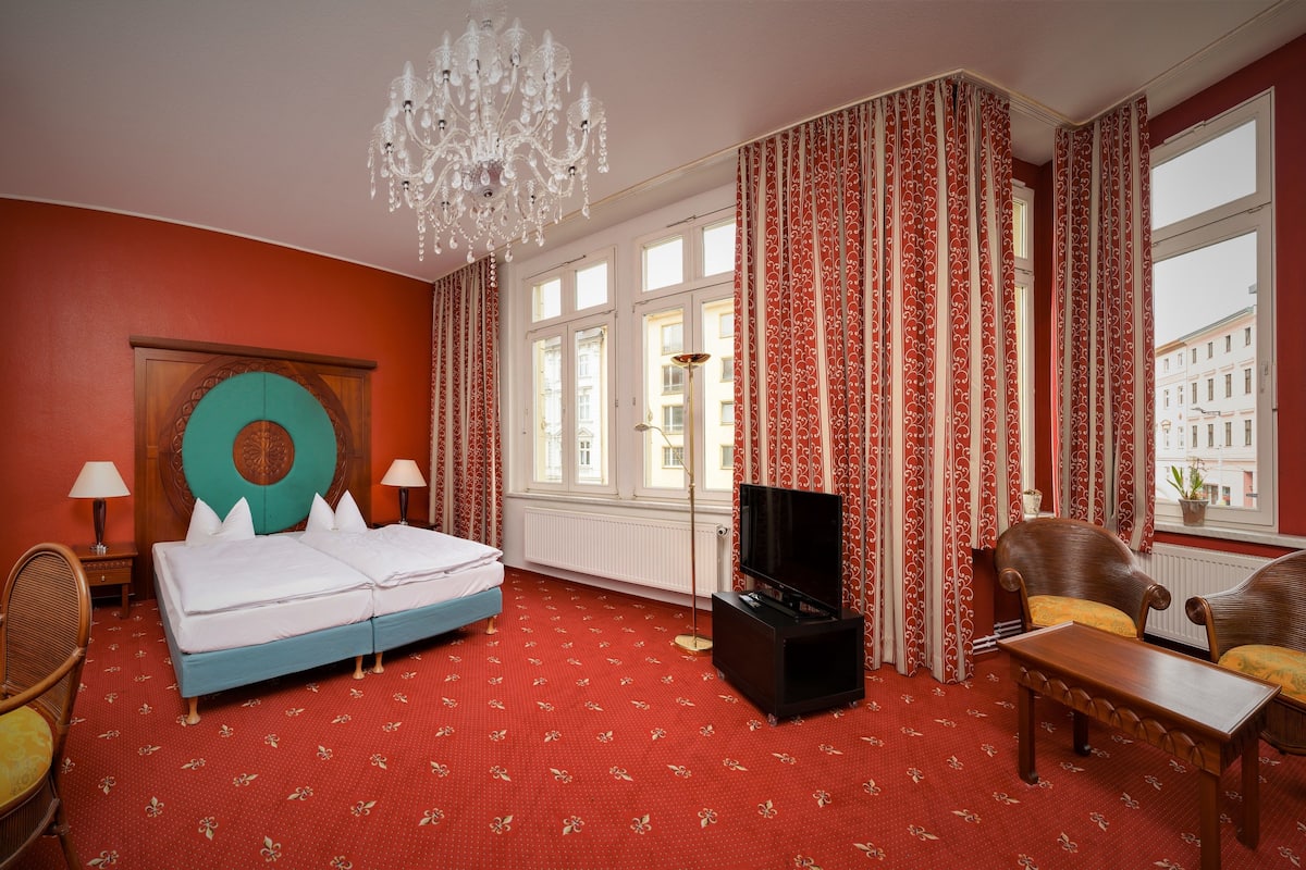 A hotel room with a bed, a TV, a desk, and a chair.