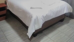 A standard hotel room with a single bed, a nightstand, and a window with curtains.