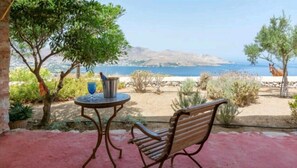A patio with a table and chair, a blue glass, and a metal bucket. - Villa Via Savoia (Leros)