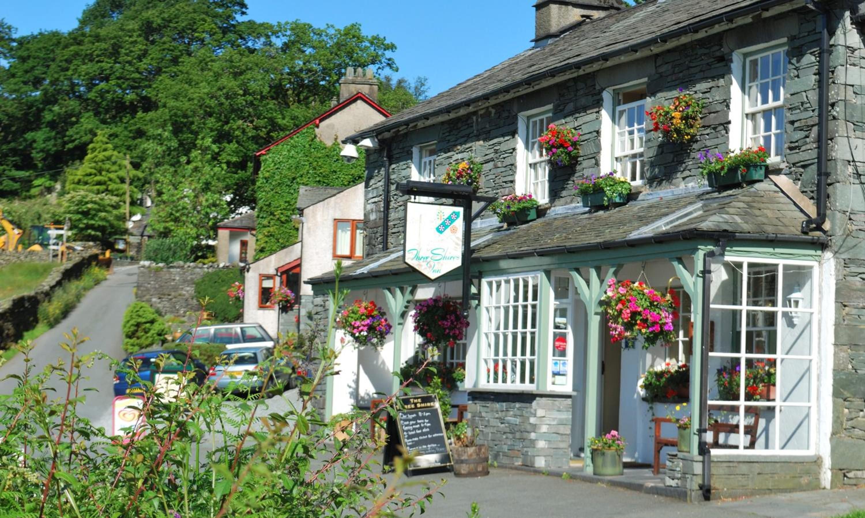 A traditional stone building with a signboard for 'The Three Shires Inn'.