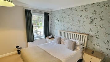 Un dormitorio con cama, mesita de noche y ventana con cortinas.