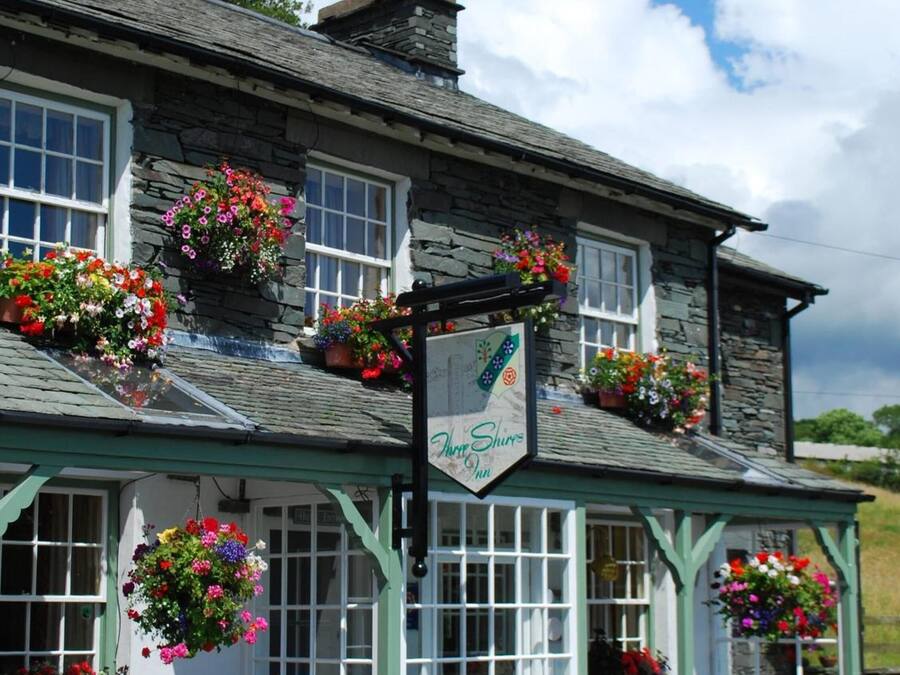 A traditional stone building with a sign reading "The Three Shires Inn".