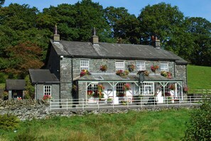 A stone house with a white porch and flower boxes.
