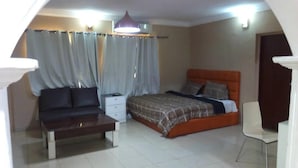 Un dormitorio con cama, mesita de noche, una silla y cortinas.