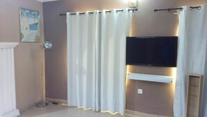 Un baño con cortina de ducha, televisor montado y lámpara de pie.