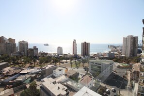 Un paisaje urbano con rascacielos, cielo despejado y una masa de agua al fondo.