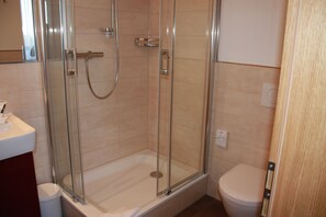 A bathroom with a glass-enclosed shower, a toilet, and a sink. - Boardinghaus Holledau Inn (Schweitenkirchen)