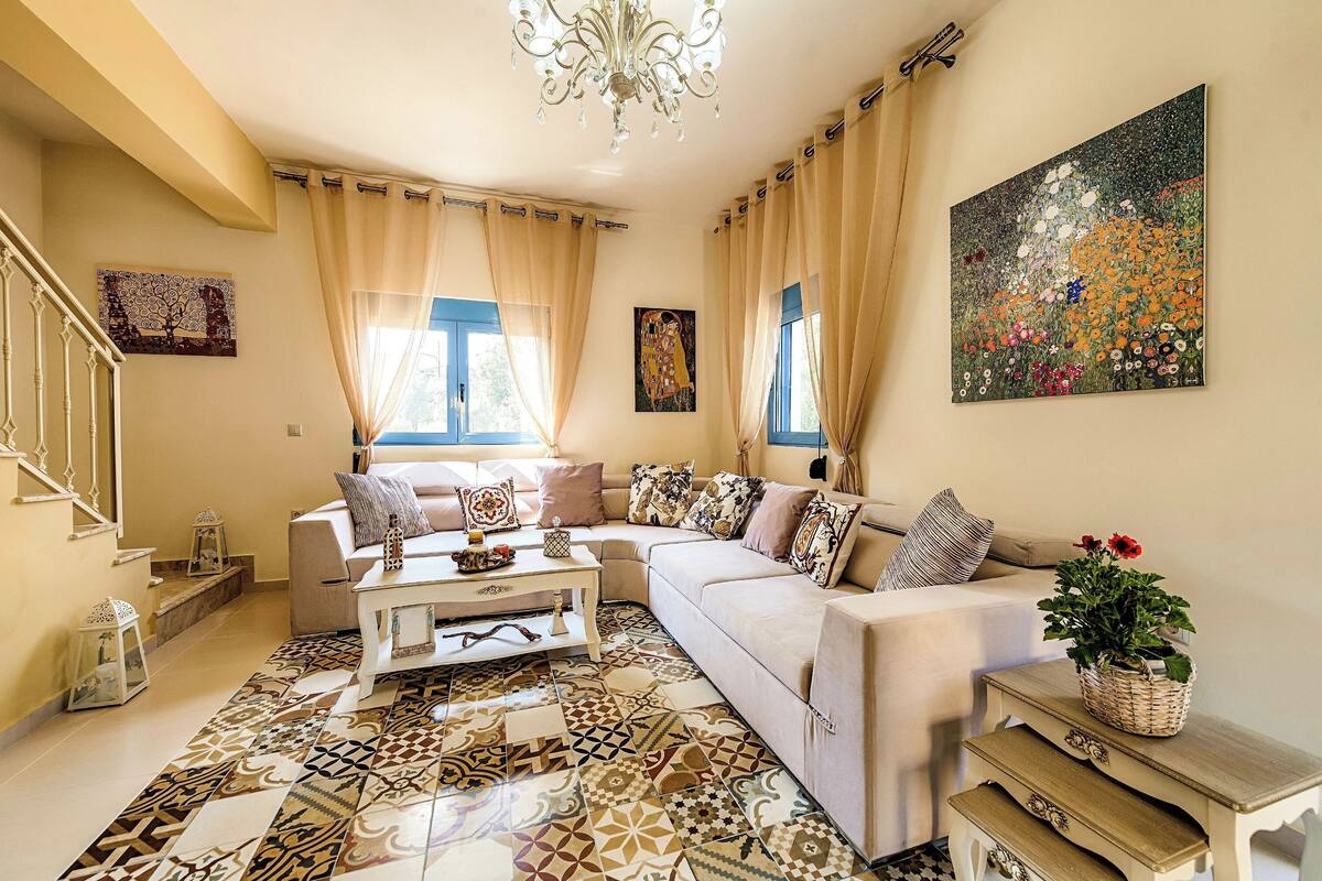 Ein Wohnzimmer mit einer Couch, einem Couchtisch, einem gemusterten Teppich und Bildern an den Wänden.
