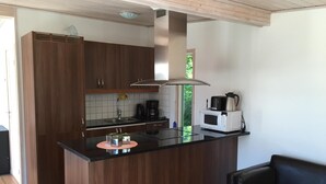 Una cocina moderna con armarios de madera, encimera negra y microondas integrado.