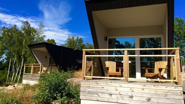Una casa moderna con terraza, amplias ventanas y mobiliario exterior.