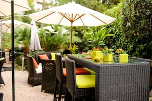 An outdoor dining area with wicker furniture, a glass table, and potted plants. - idealsejour (Cannes)