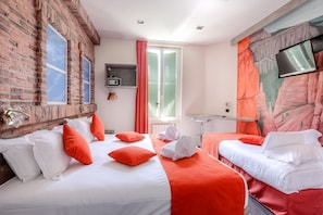 A hotel room with two beds, a brick wall, a window with shutters, a flat-screen TV, and a mural on the wall. - idealsejour (Cannes)
