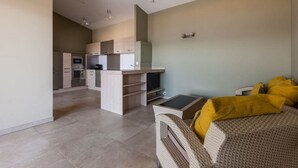 A modern living room with a sofa, a TV, and a kitchen area in the background.