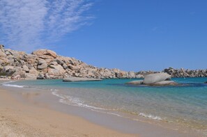 Une plage avec de gros rochers et une eau turquoise cristalline.