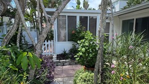 Un sentier de jardin qui mène à une maison avec une clôture blanche et une fenêtre à volets.