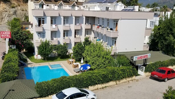 Un hotel de varios pisos con piscina, asientos al aire libre y un letrero que indica el nombre del hotel.