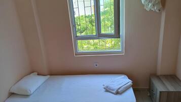 Una habitación pequeña con cama individual y ventana con vista a follaje.