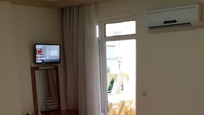 Habitación de hotel con dos camas, un televisor sobre un soporte de madera y un equipo de aire acondicionado en la pared.