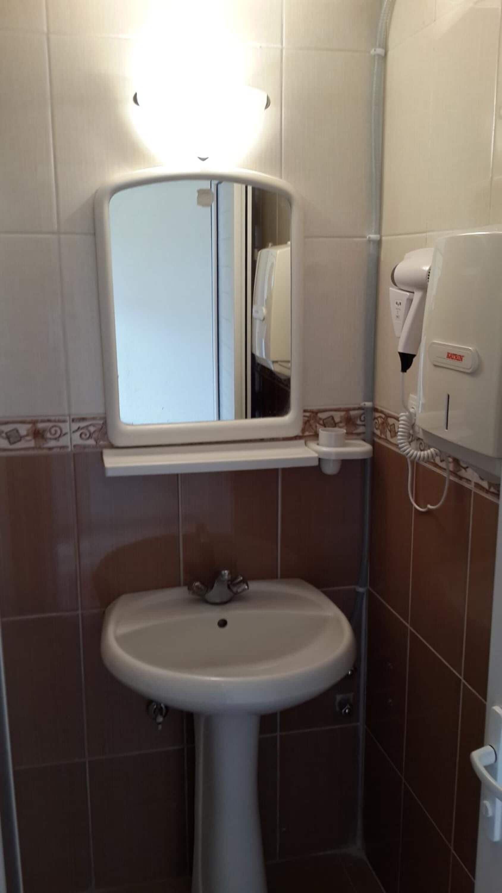 A bathroom with a white sink, a mirror, and a hand dryer.