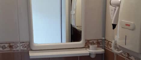 A bathroom with a white sink, a mirror, and a hand dryer.