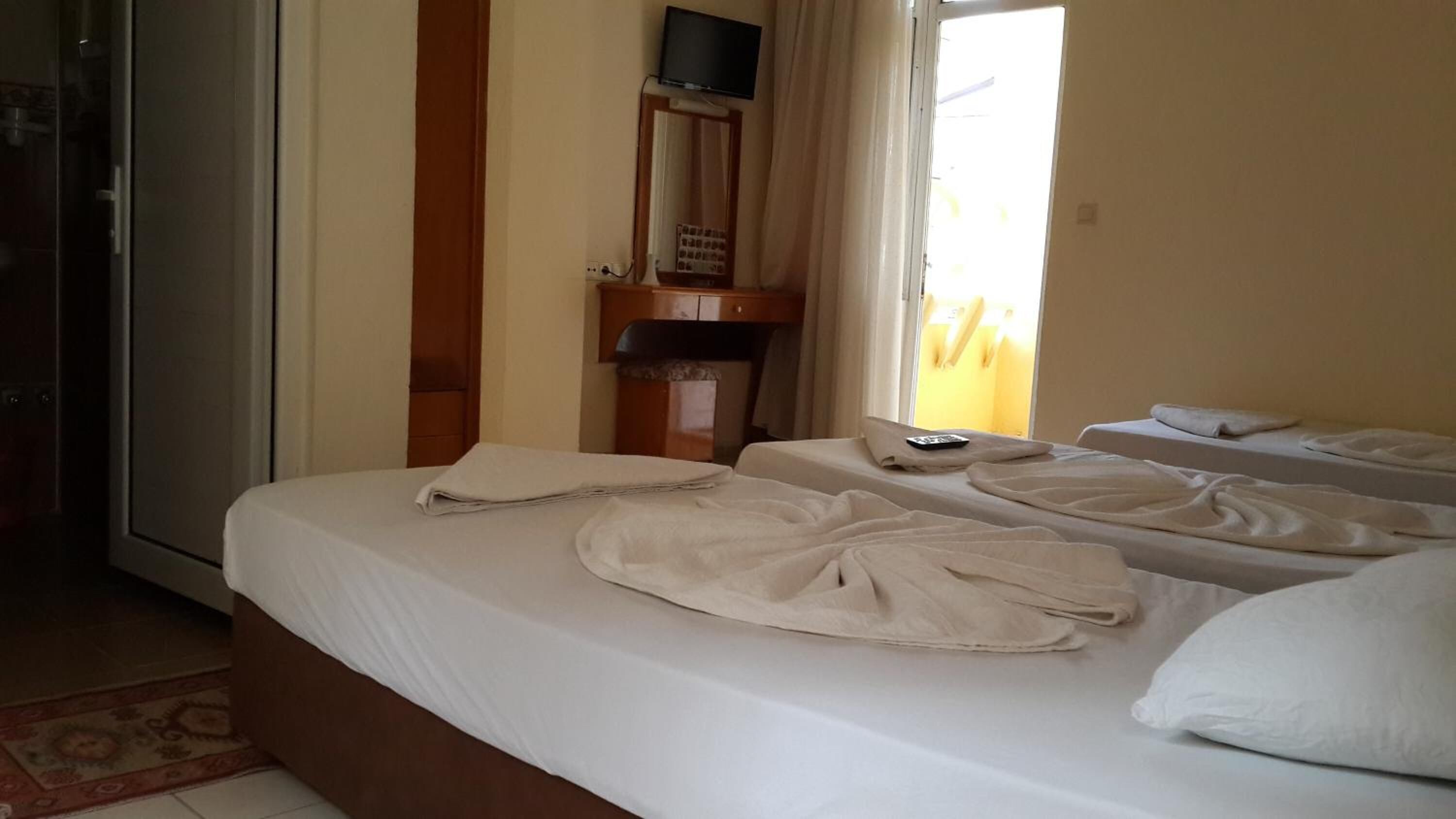 Habitación de hotel con dos camas, un televisor en la pared y una ventana con cortinas.