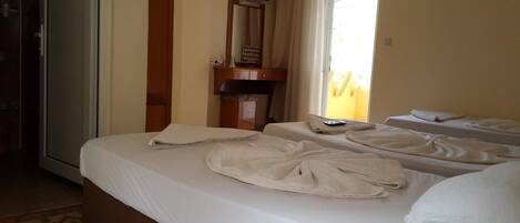 Habitación de hotel con dos camas, un televisor en la pared y una ventana con cortinas.