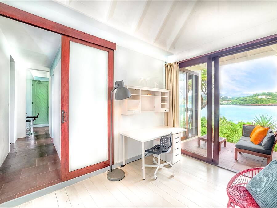 A modern room with a desk, chair, and a view of the sea.