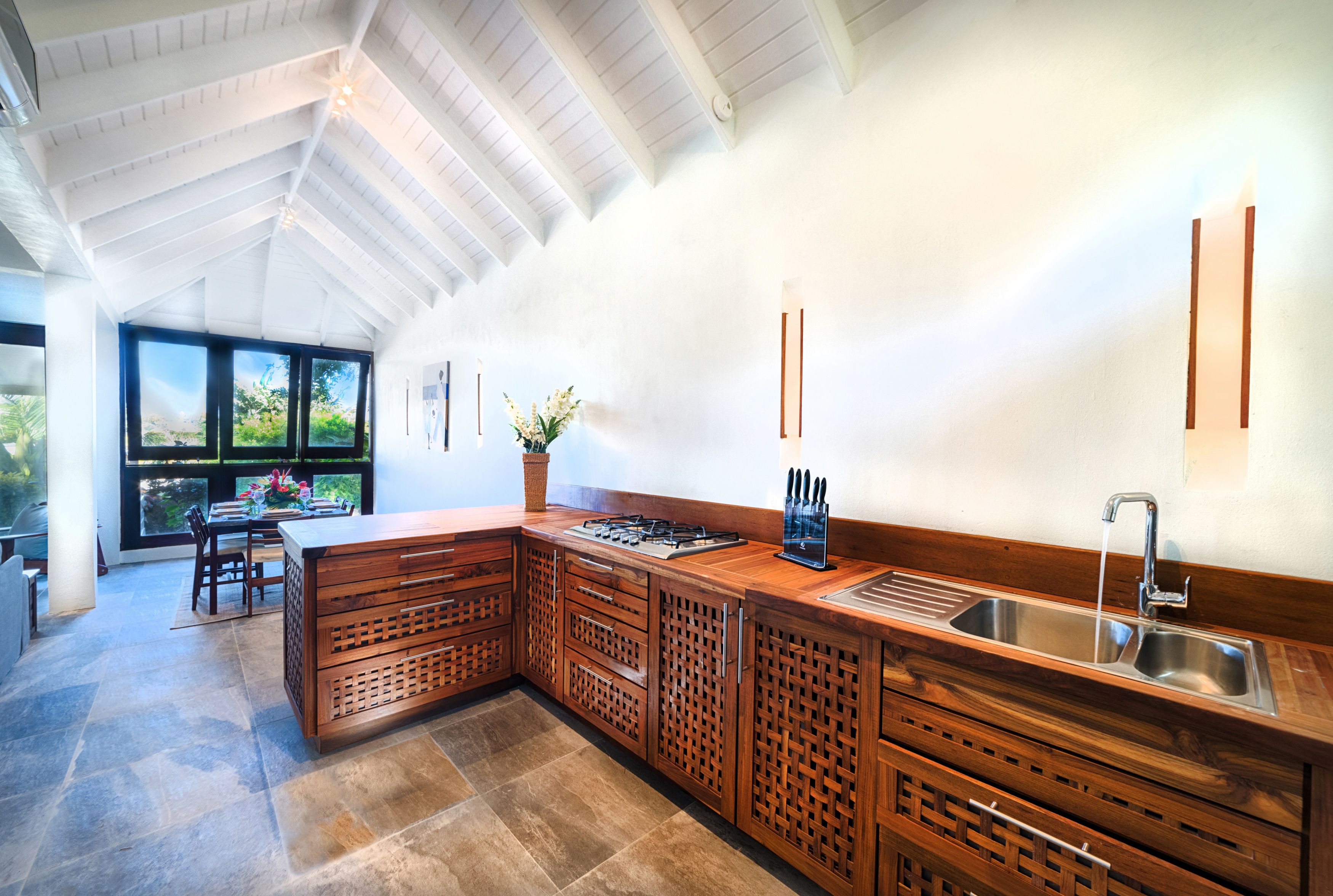 A modern kitchen with a large island, built-in cabinets, and a large window providing a view of the outdoors.