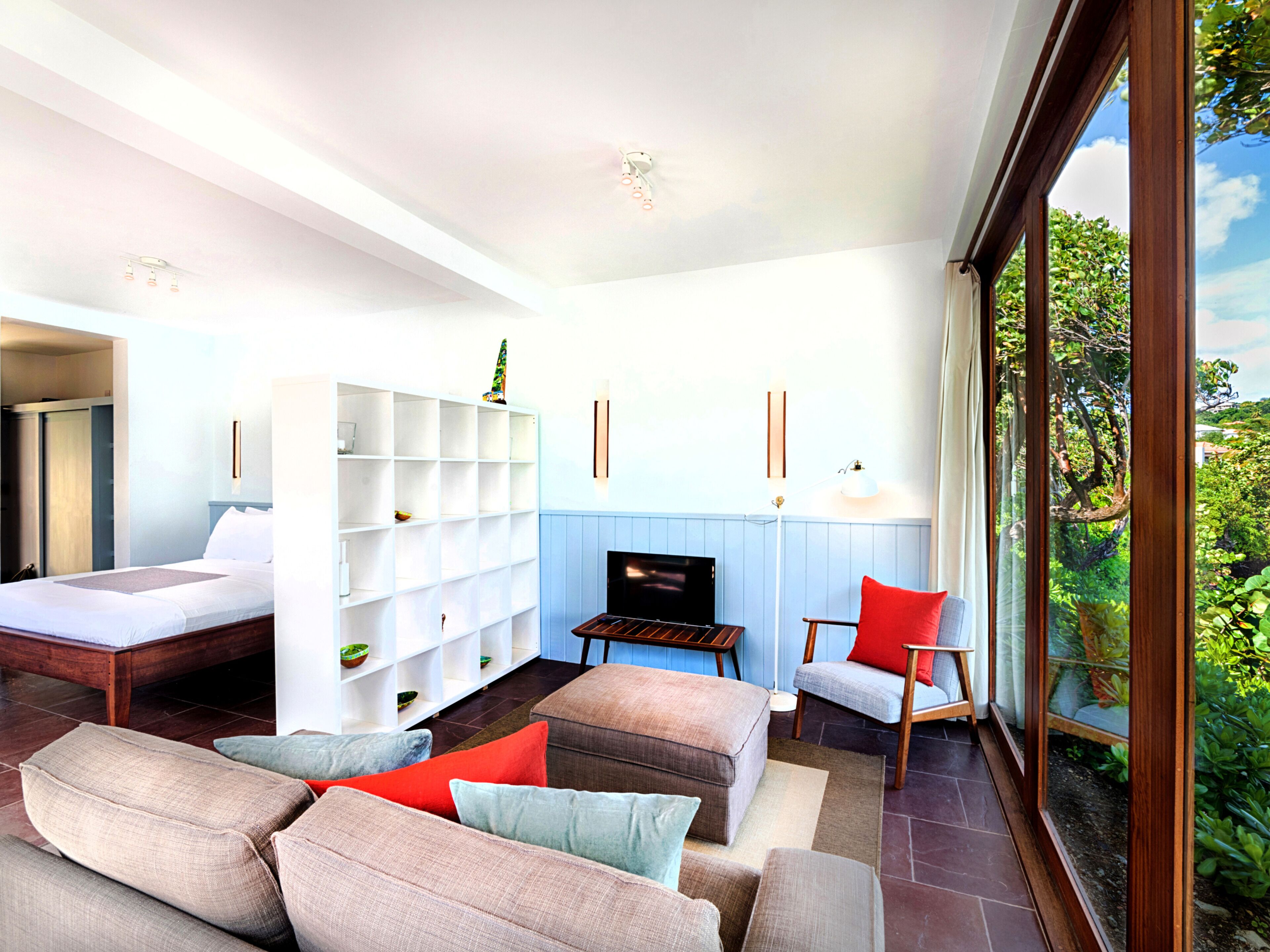 A modern living room with a sofa set, a flat-screen TV, and a bookshelf.