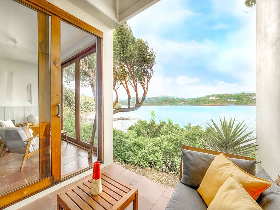 Un balcón con vistas al mar, una mesa de madera y un sofá con cojines.