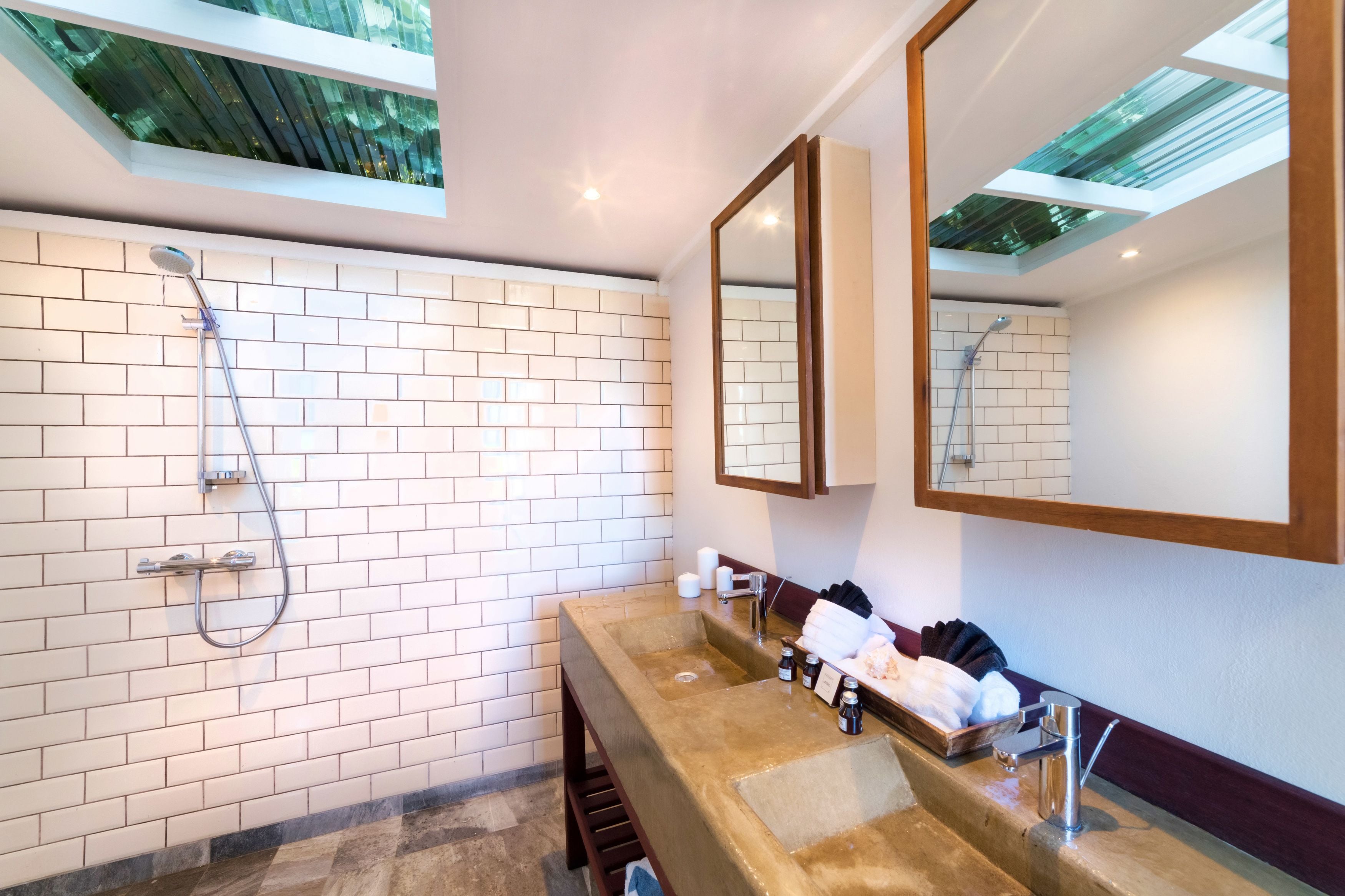A modern bathroom with a large shower, a sink with a mirror, and a window above the shower.