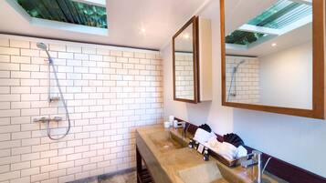 A modern bathroom with a large shower, a sink with a mirror, and a window above the shower.