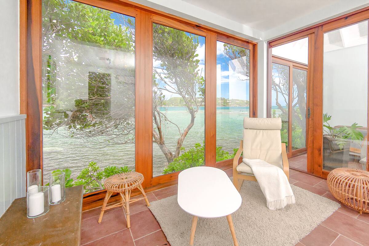A room with large glass doors, a white chair, a small round table, and a white rug.