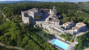 A castle-like structure with a swimming pool and lounge chairs. - Castello di Titignano (Orvieto)