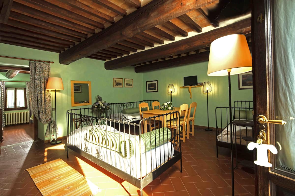 A room with a bed, a table, chairs, a lamp, and a door with a keyhole.