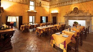 A spacious dining hall with multiple tables set for a meal, featuring ornate wall decorations and a large fireplace. - Castello di Titignano (Orvieto)
