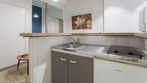 A modern kitchen with a built-in sink, a stove, and a small dining area with a chair. - Up to 6 people in the heart of Old Lyon (Lyon)